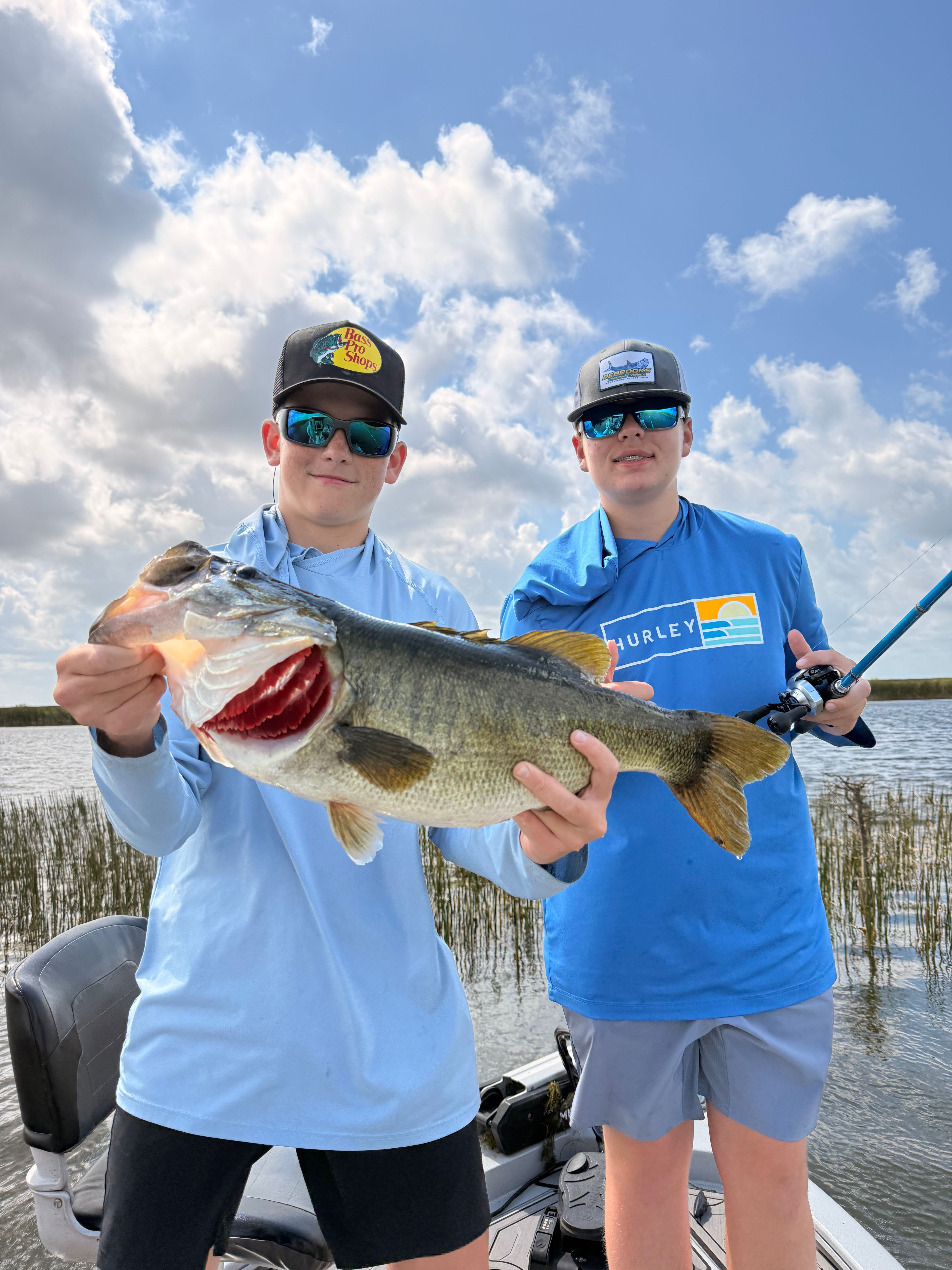 Two anglers holding a large bass fish on a boat in Fellsmere FL