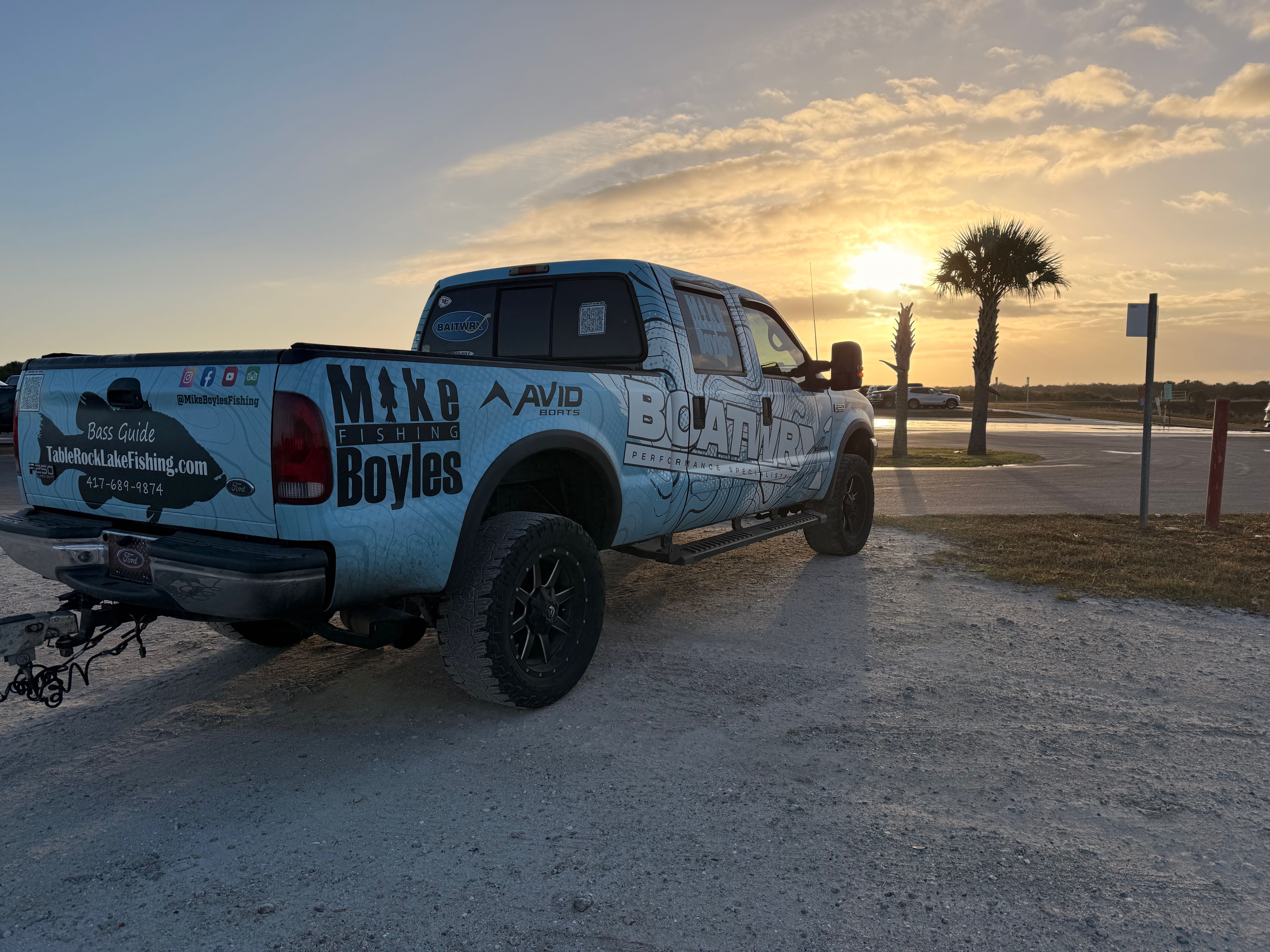 Fishing guide truck with custom wrap and boat trailer parked at sunset in Fellsmere FL