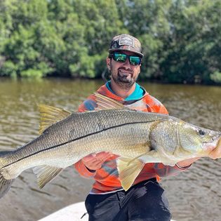A fisherman holding a large Snook fish in Tampa