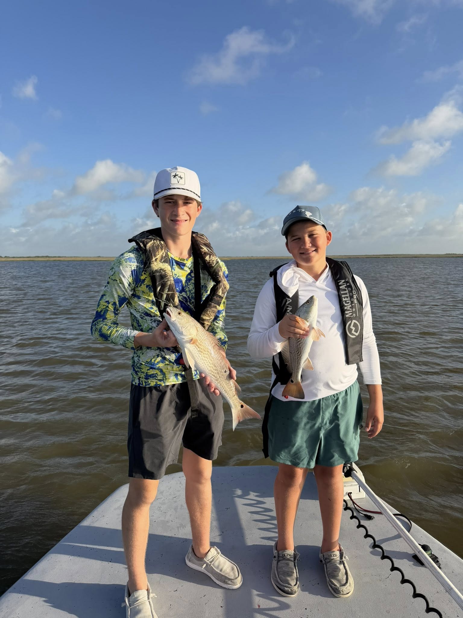 Two young anglers displaying caught redfish on boat in Matagorda TX waters