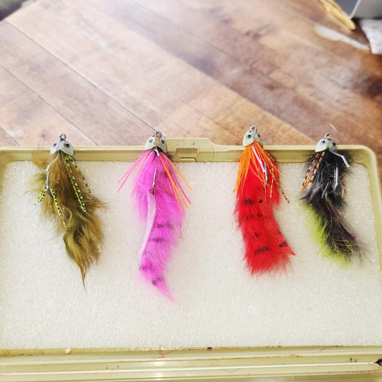 Four colorful fishing lures with feathers displayed in tackle box in Alba TX