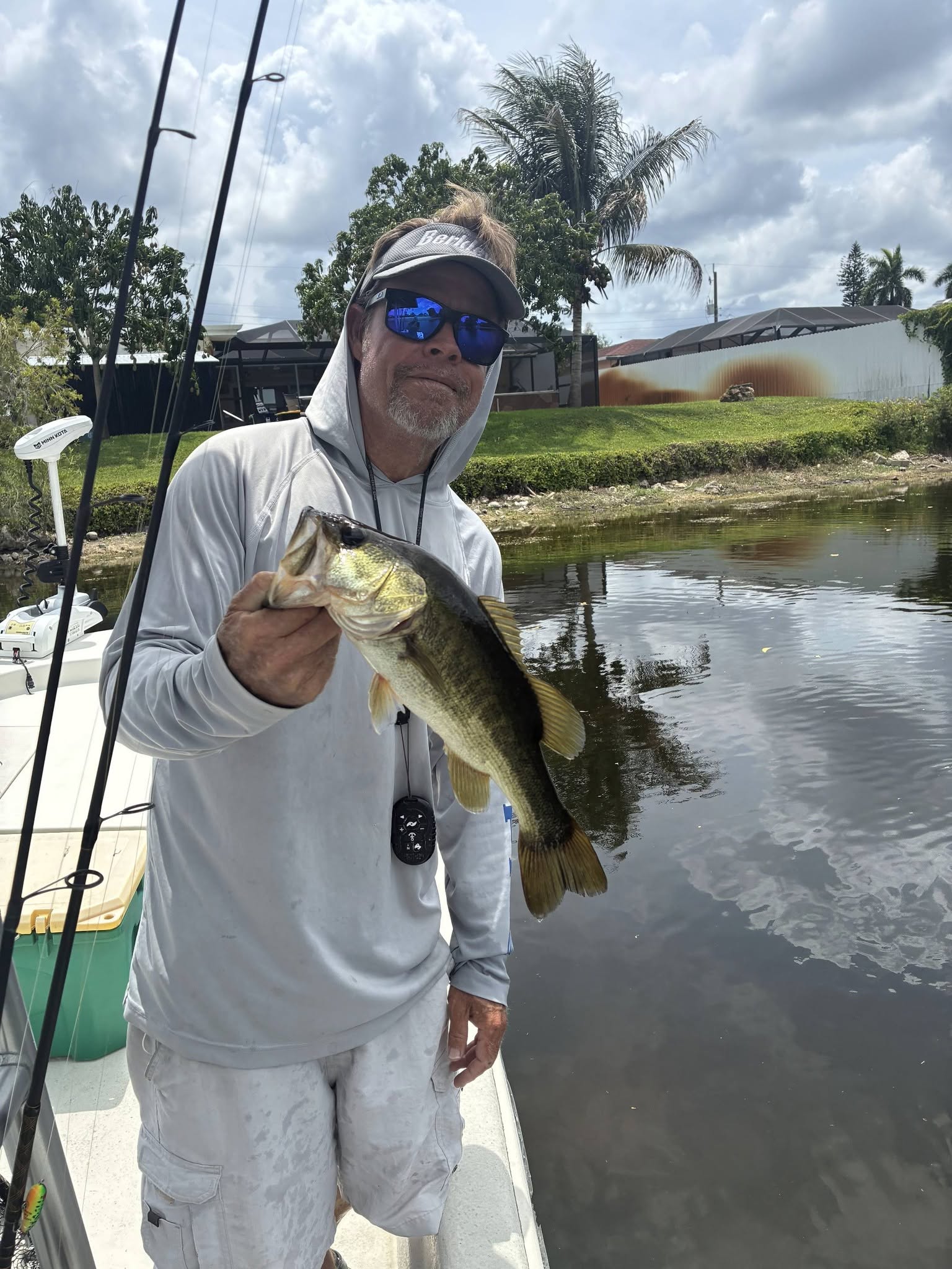 Angler holding caught bass fish on boat in Bonita Springs FL waterway