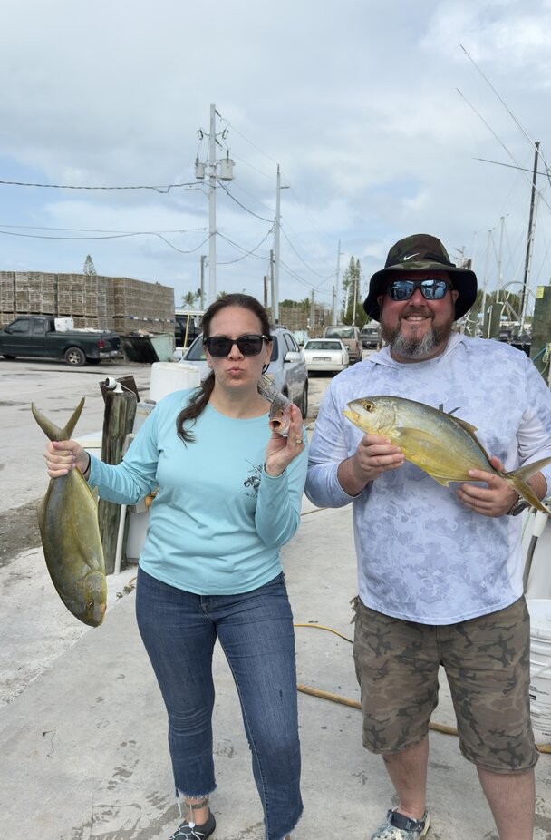 Two anglers displaying their caught fish at a marina in Marathon FL