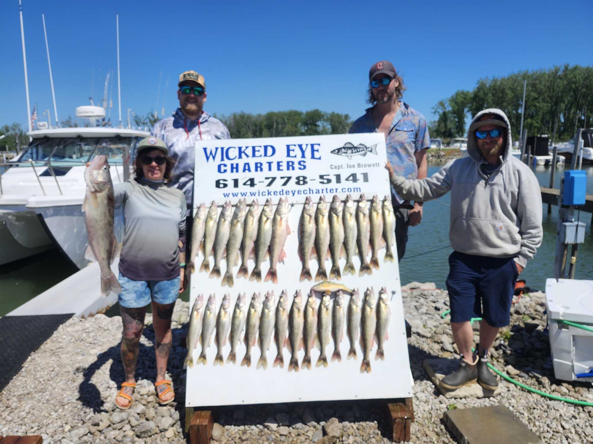 Large walleye fishing catch displayed on cleaning table at Marblehead OH marina with charter boat in background