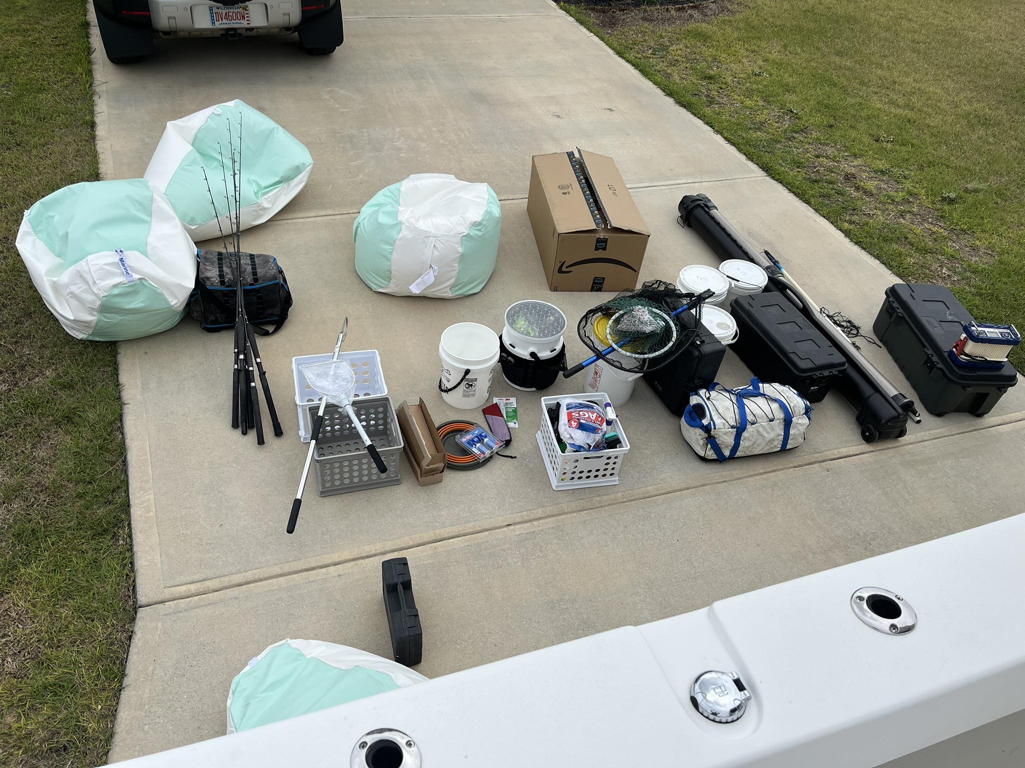Fishing equipment and gear laid out on concrete driveway including tackle boxes, rods, and storage containers at Okaloosa Island FL