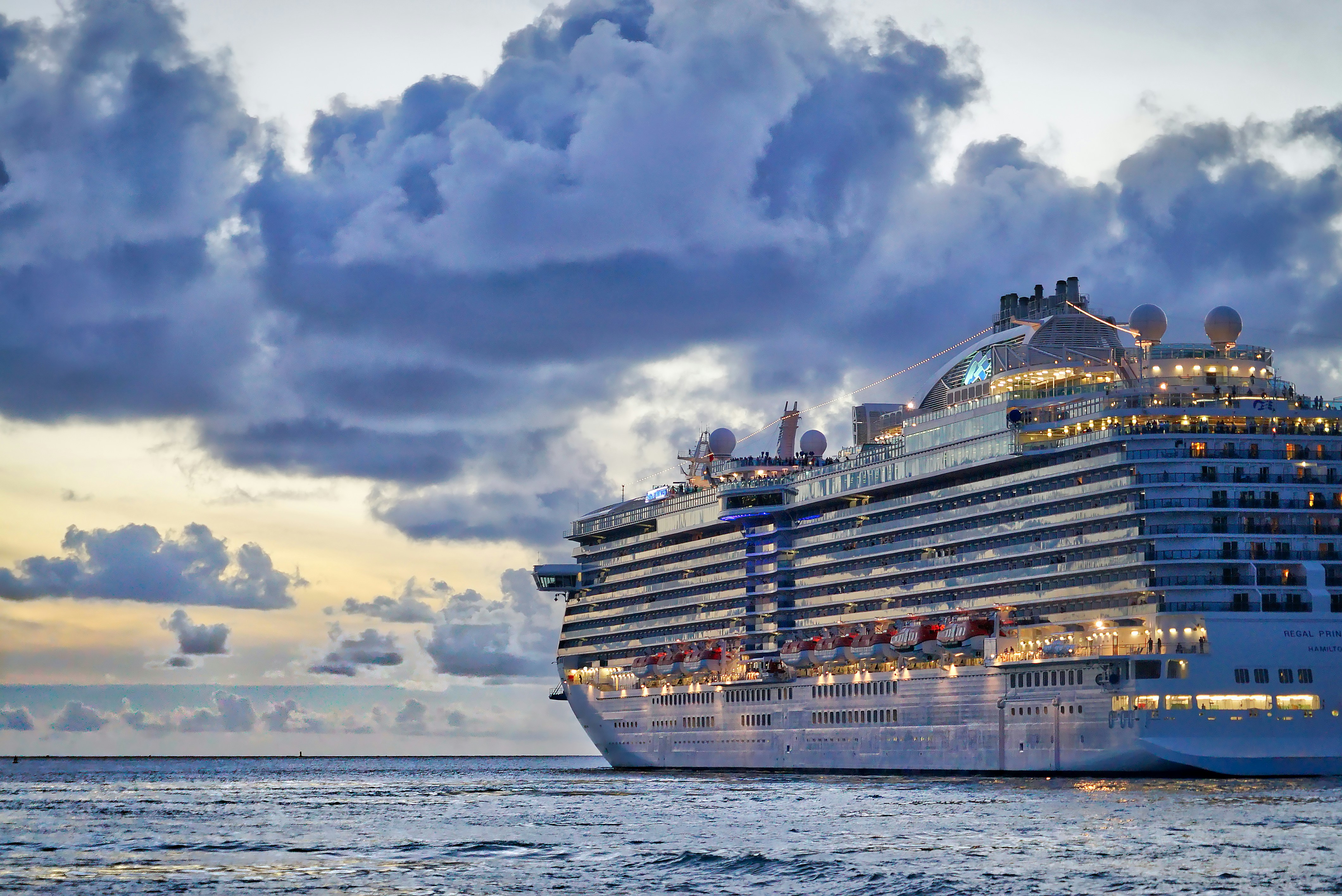 Large cruise ship sailing on ocean waters near Chennai Tamil Nadu with dramatic cloudy sky at sunset