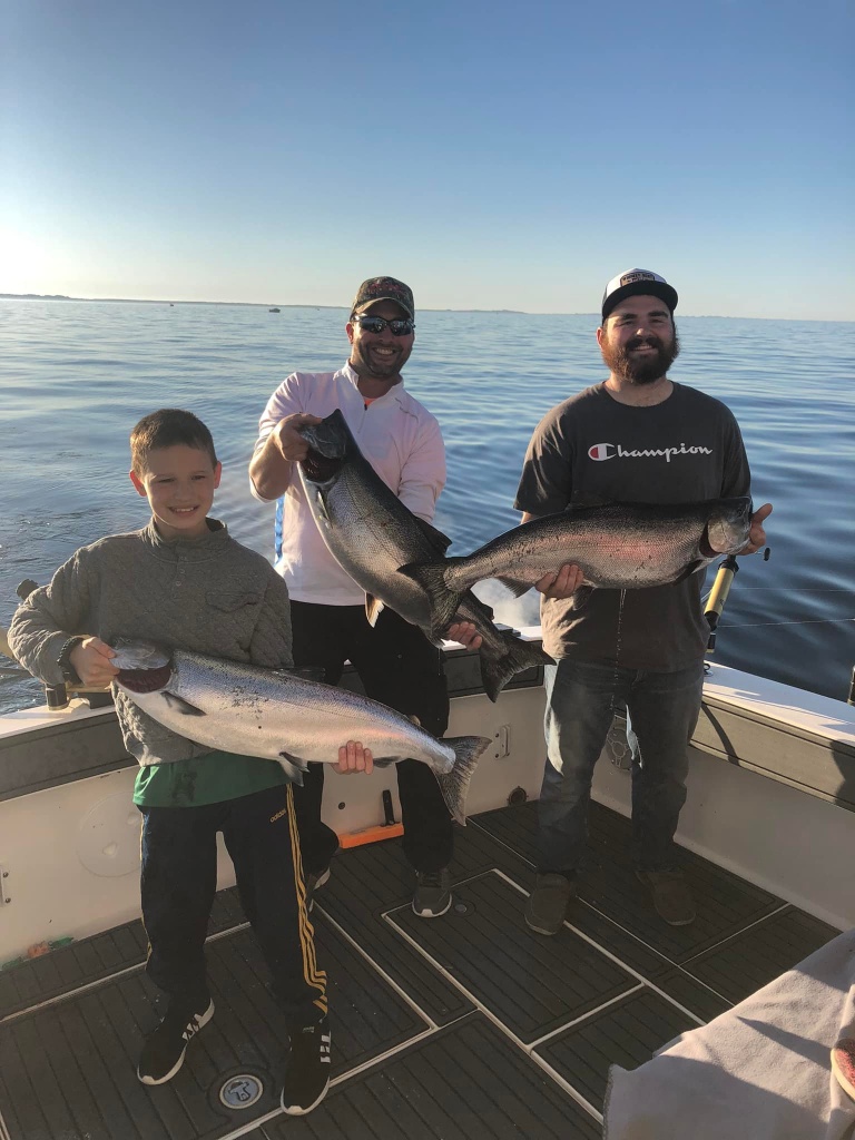 Three anglers holding big fish in MI