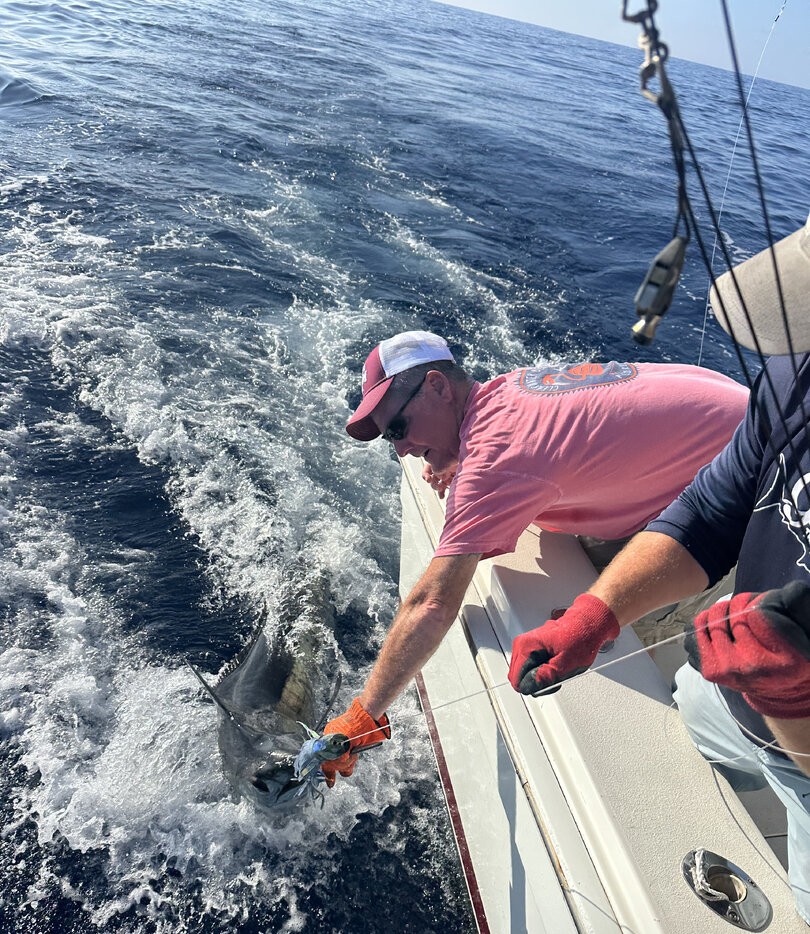 Angler releasing a fish back into the ocean waters off Kailua-Kona Hawaii during sportfishing charter