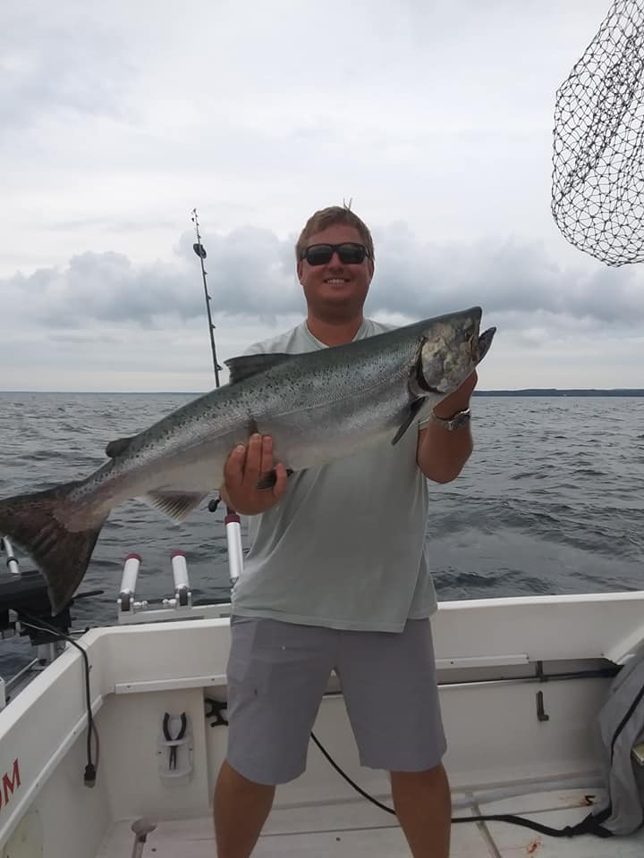 An angler catches a large rainbow trout in Oswego
