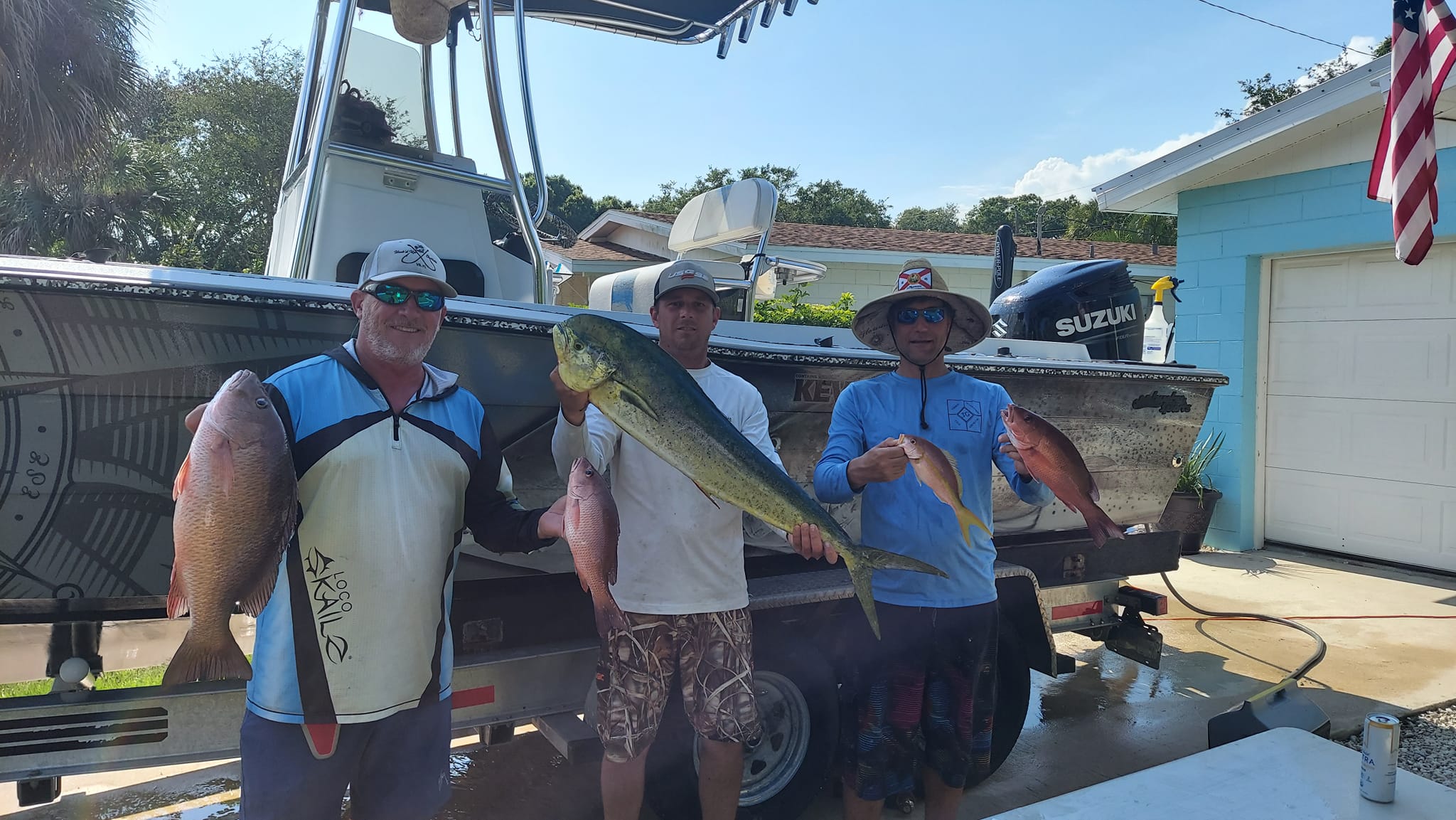 Three anglers displaying their catch of mahi mahi and grey snapper after fishing trip in Vero Beach FL