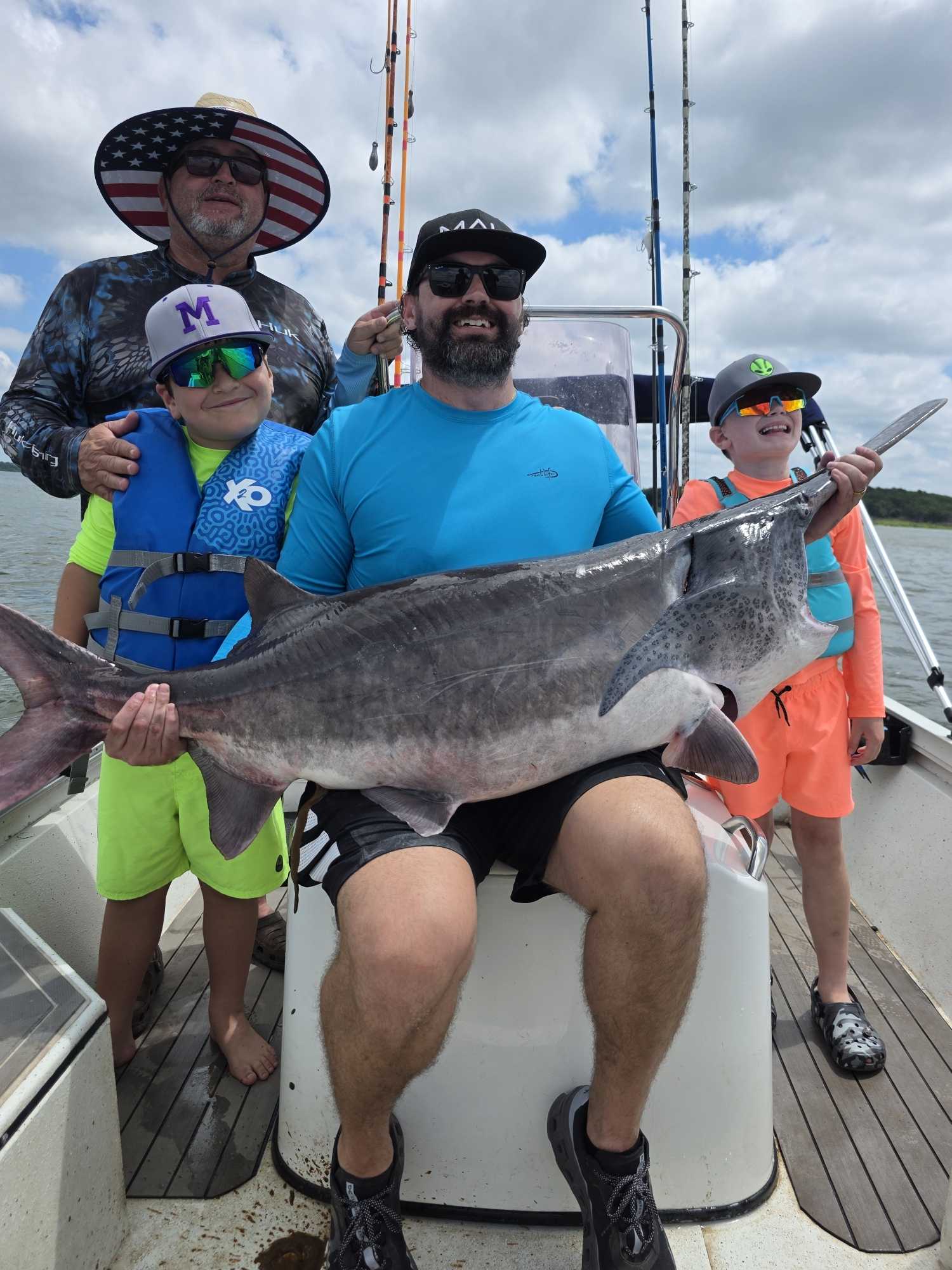 Fishing group displaying large catfish catch on boat in Glencoe OK