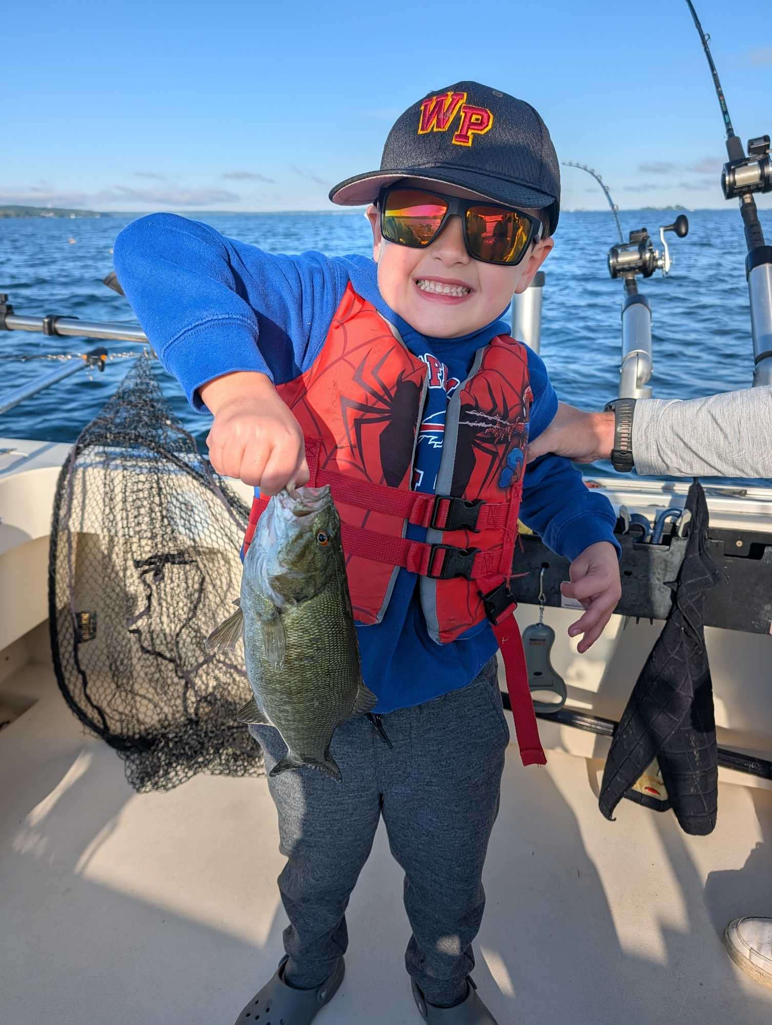 Smallmouth bass catch on fishing boat in Henderson NY with fishing equipment and net visible