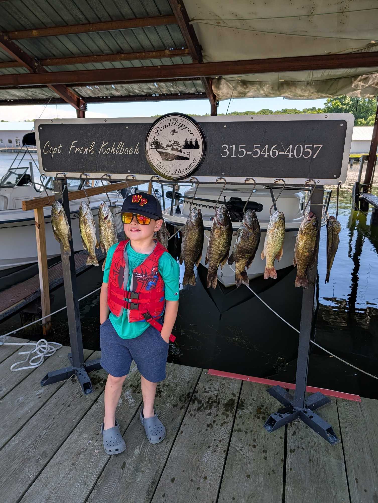 Successful smallmouth bass fishing charter display with multiple fish hanging on cleaning station in Henderson NY