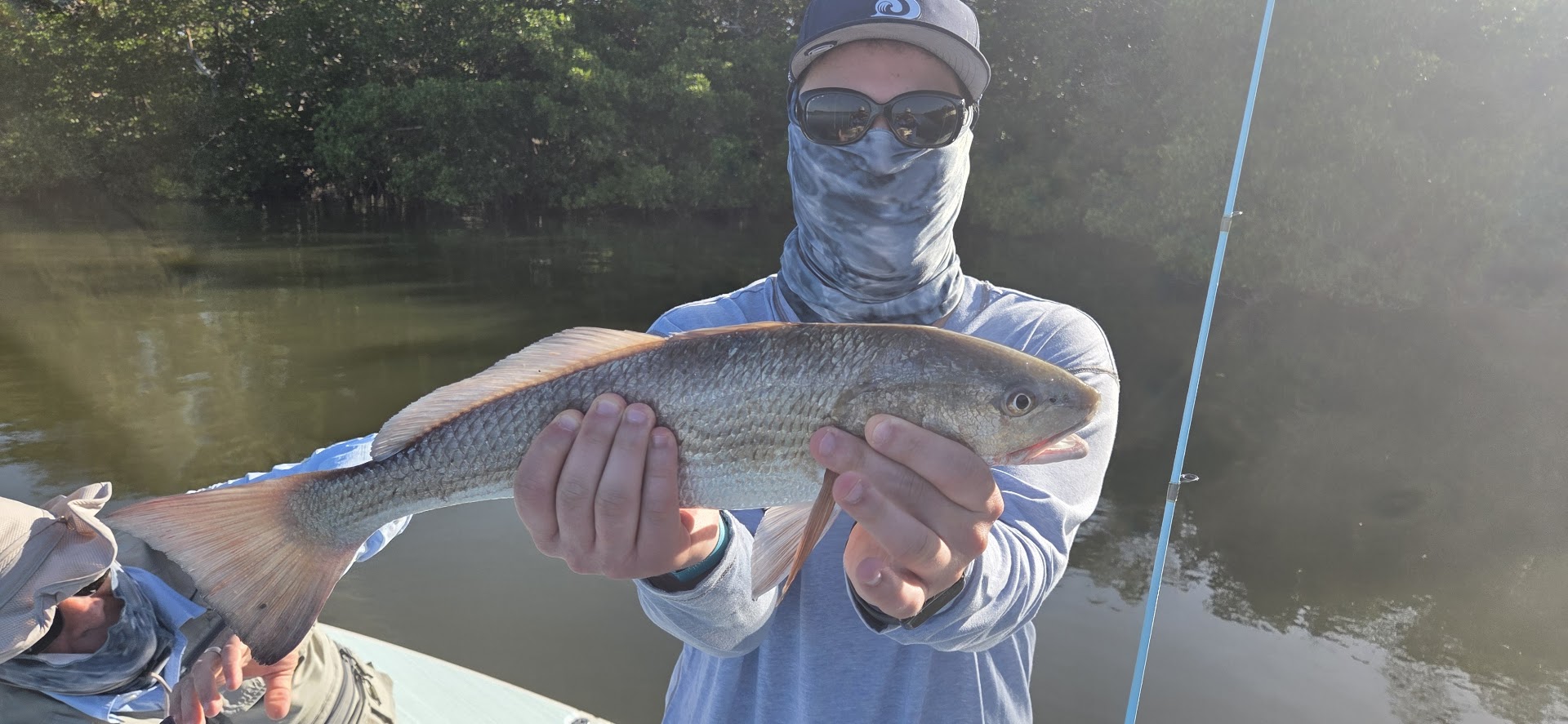 Angler holding caught redfish on fishing boat in Naples FL waters