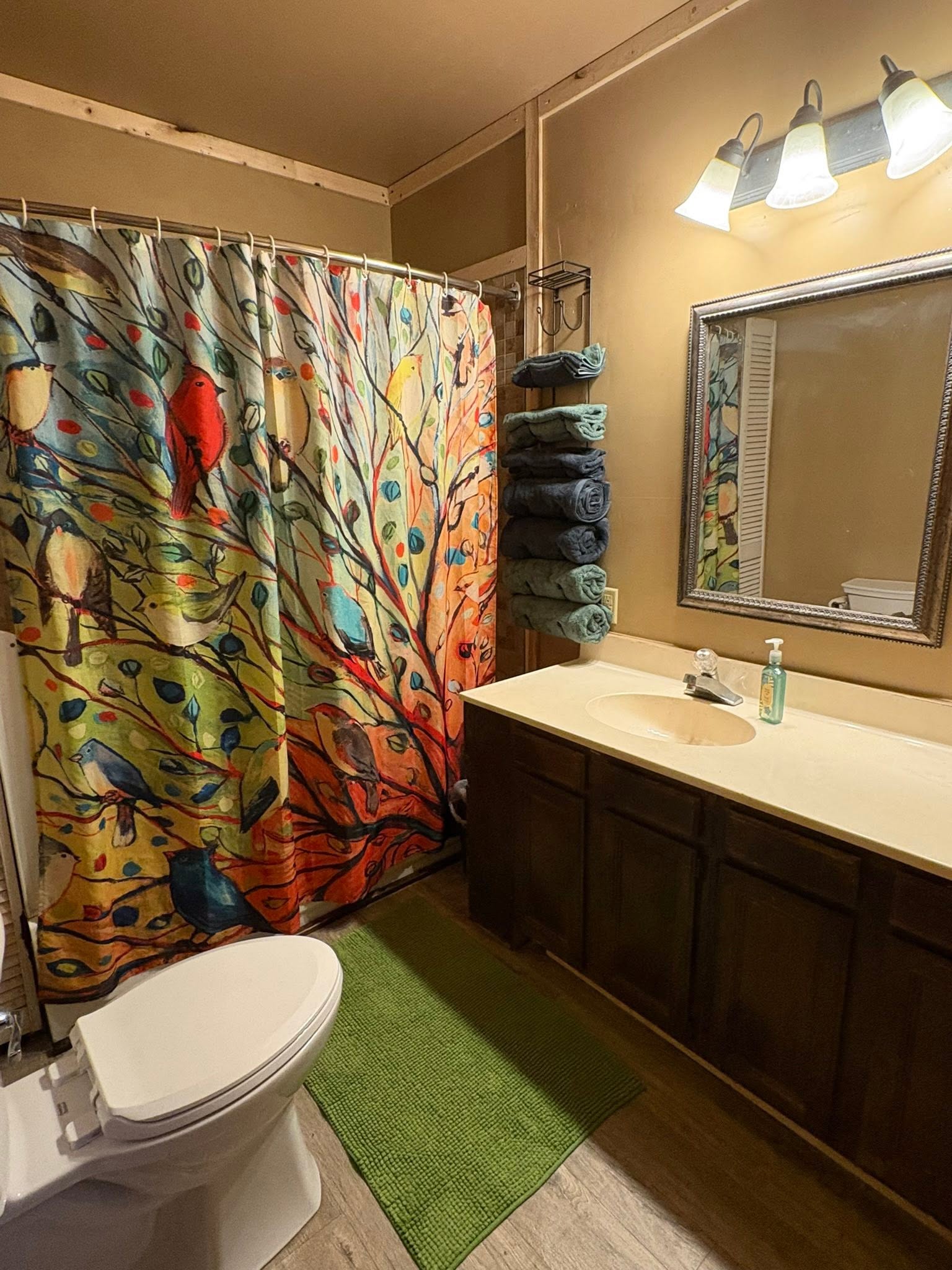 Colorful bathroom interior with artistic tree-themed shower curtain featuring birds and nature motifs in Hale MI