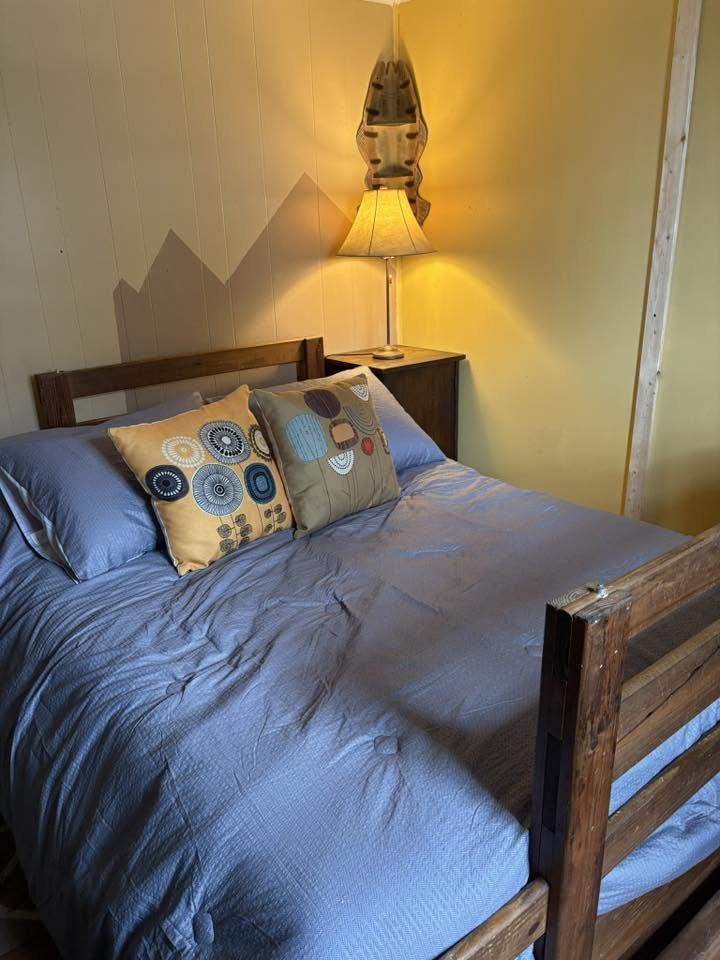 Cozy bedroom with wooden bunk bed, lamp, and decorative pillows in Hale MI fishing lodge