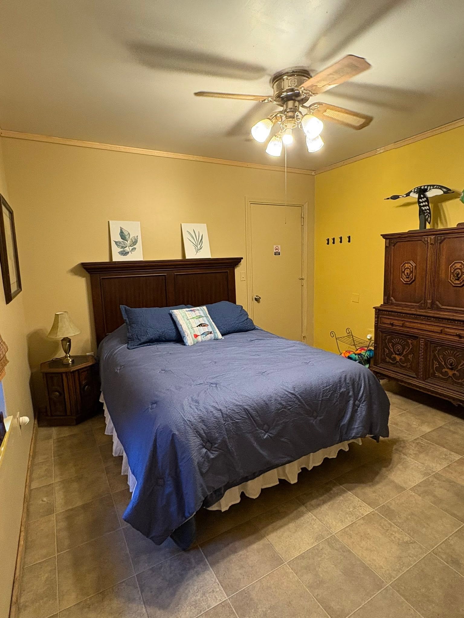 Comfortable bedroom with blue bedding and dark wood furniture in Hale MI fishing accommodation