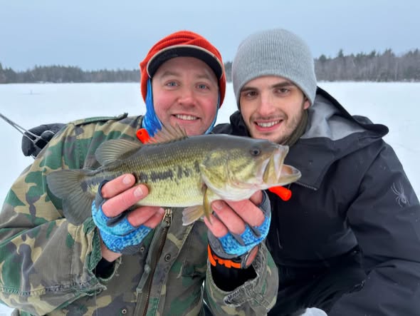 Ice fishing catch displaying bass on frozen lake in Poland ME