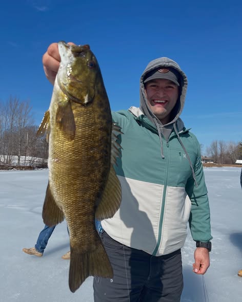 Smallmouth bass catch displayed in snowy winter fishing scene in Poland ME