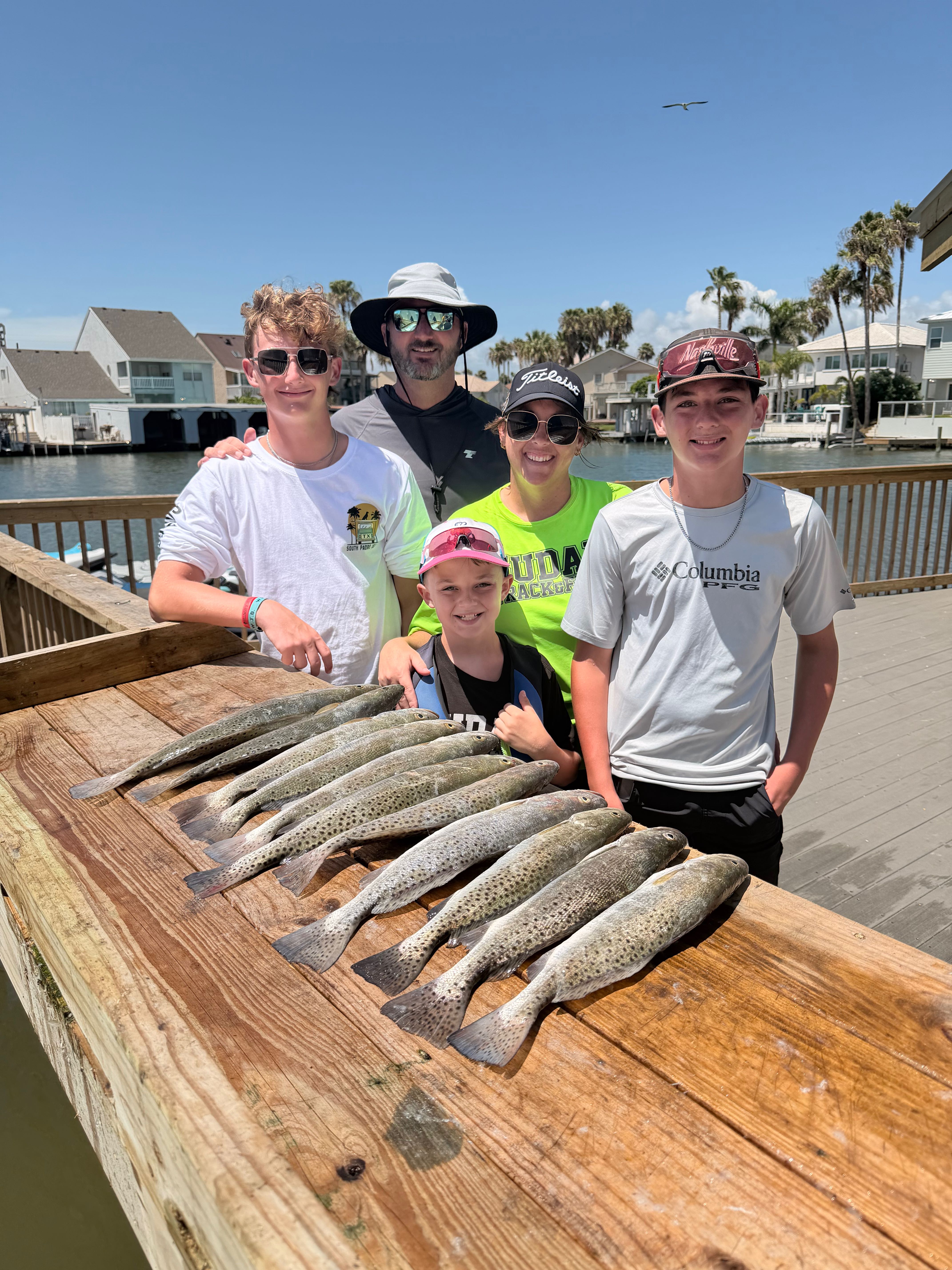 Family fishing trip showing fresh caught speckled trout on wooden dock at South Padre Island TX