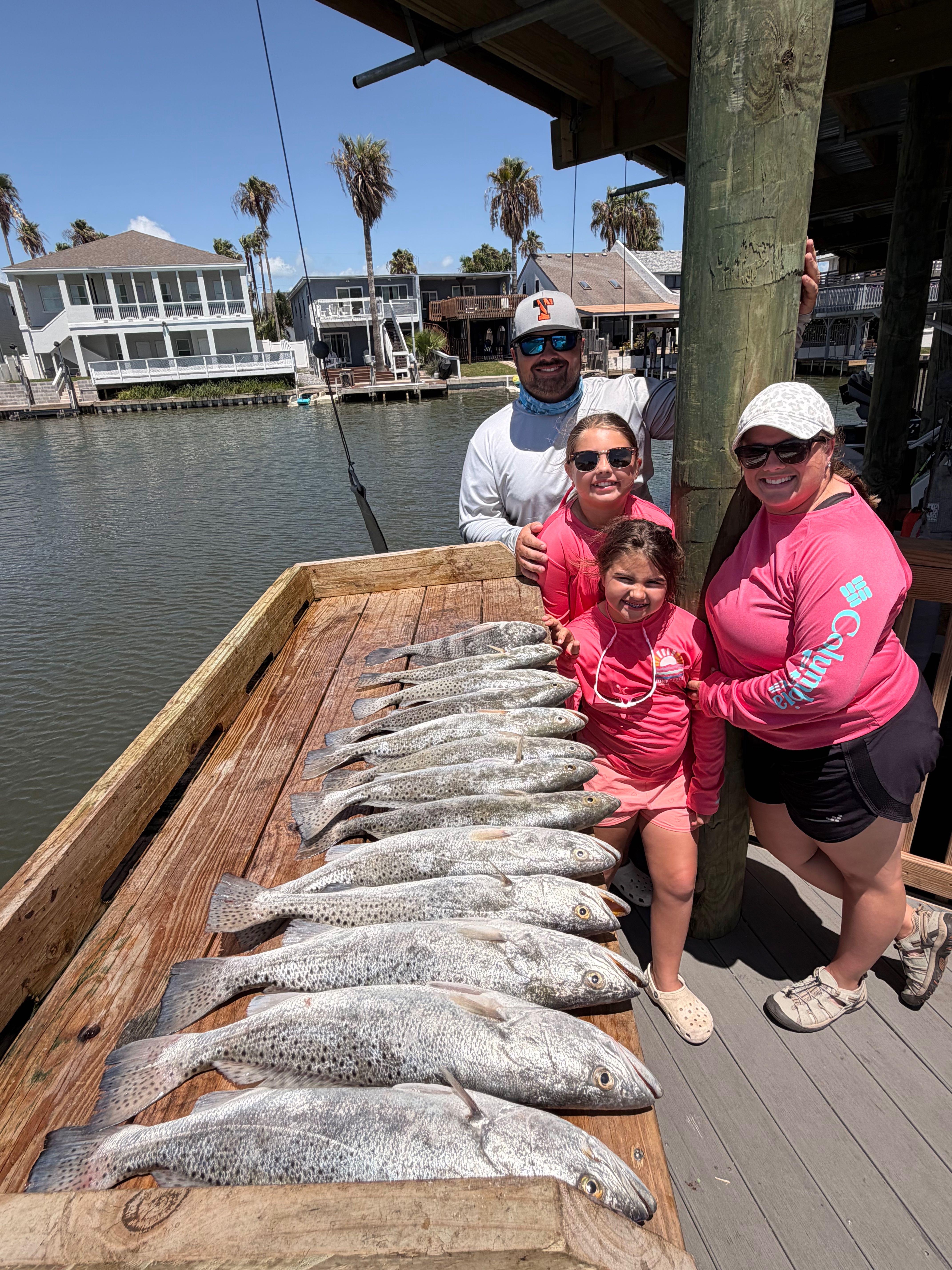 Successful speckled trout fishing trip displaying multiple caught fish on wooden dock at South Padre Island TX