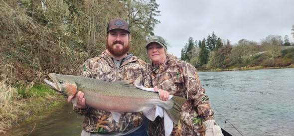 Two anglers displaying a large rainbow trout catch from Myrtle Creek OR fishing trip