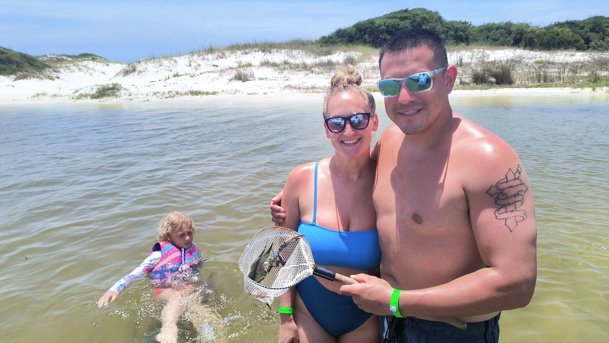 Fishing net with caught fish in shallow water near Orange Beach AL shoreline with sand dunes