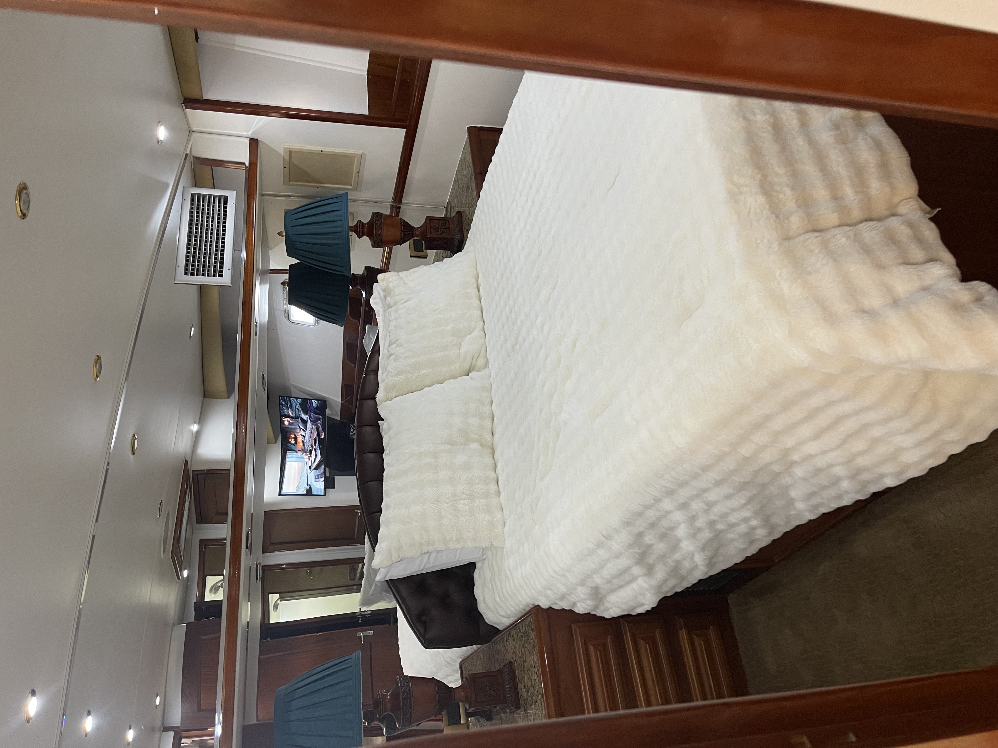 Cruise ship cabin interior with white bedding and wooden furnishings in San Diego