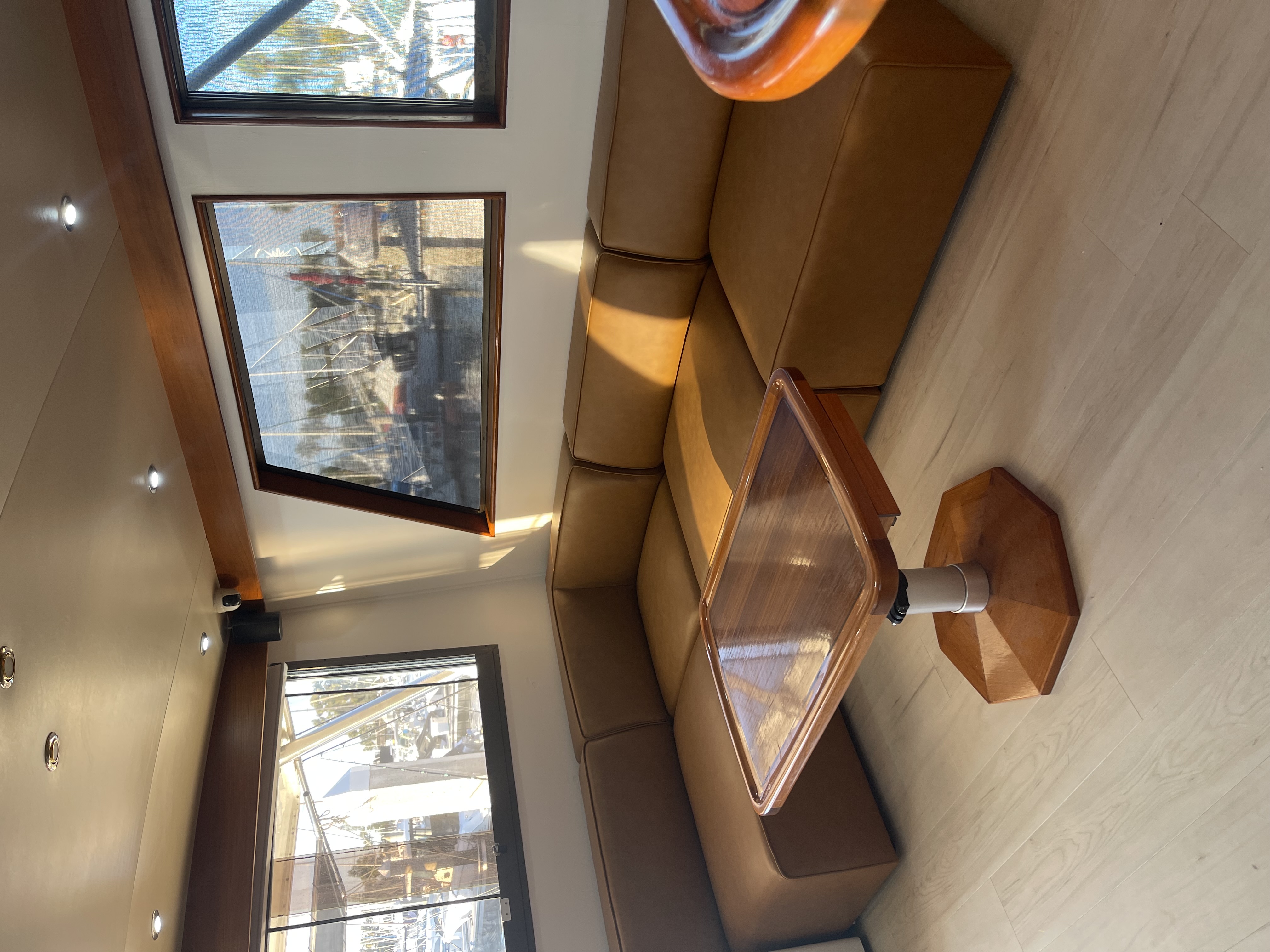 Luxury boat interior with beige seating, wooden table, and marina views through windows in San Diego CA
