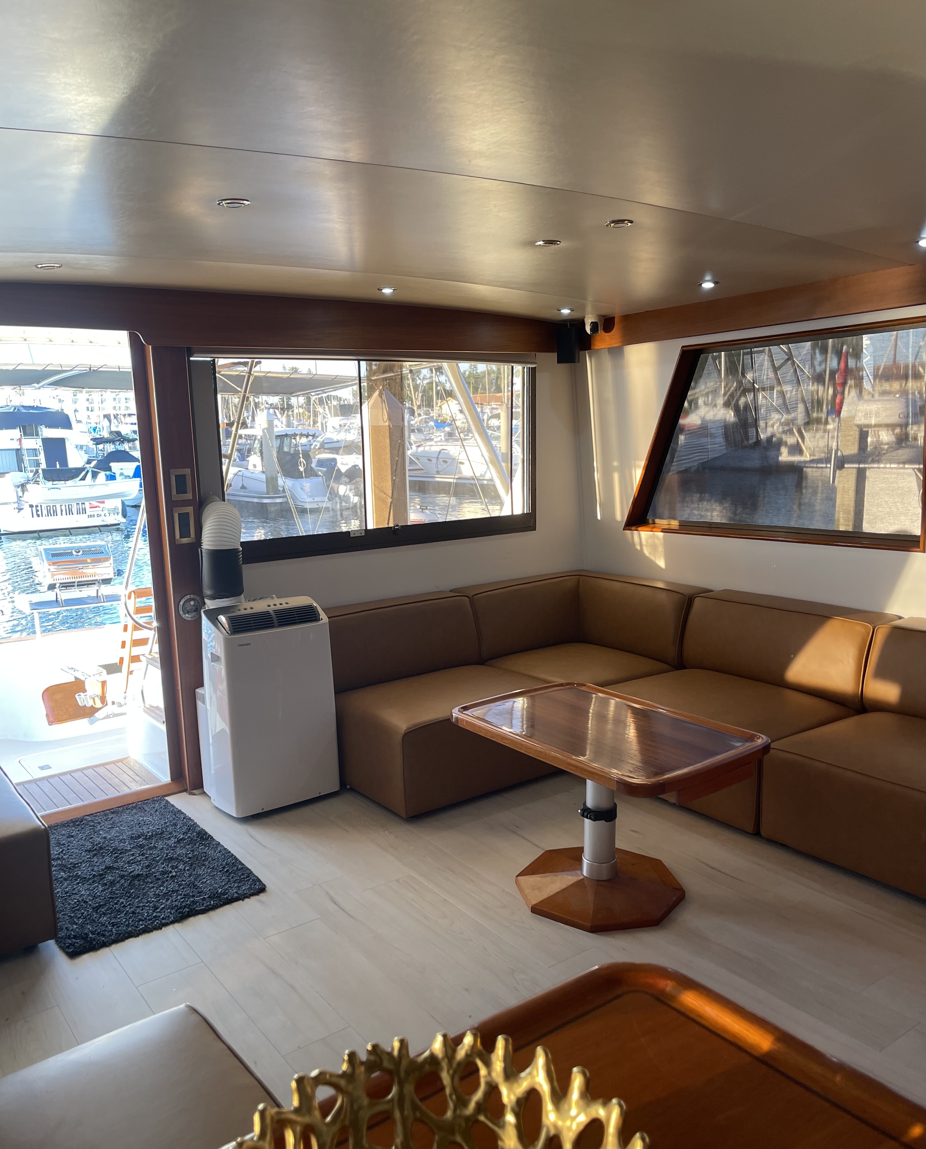 Modern boat interior with seating area and windows overlooking San Diego marina