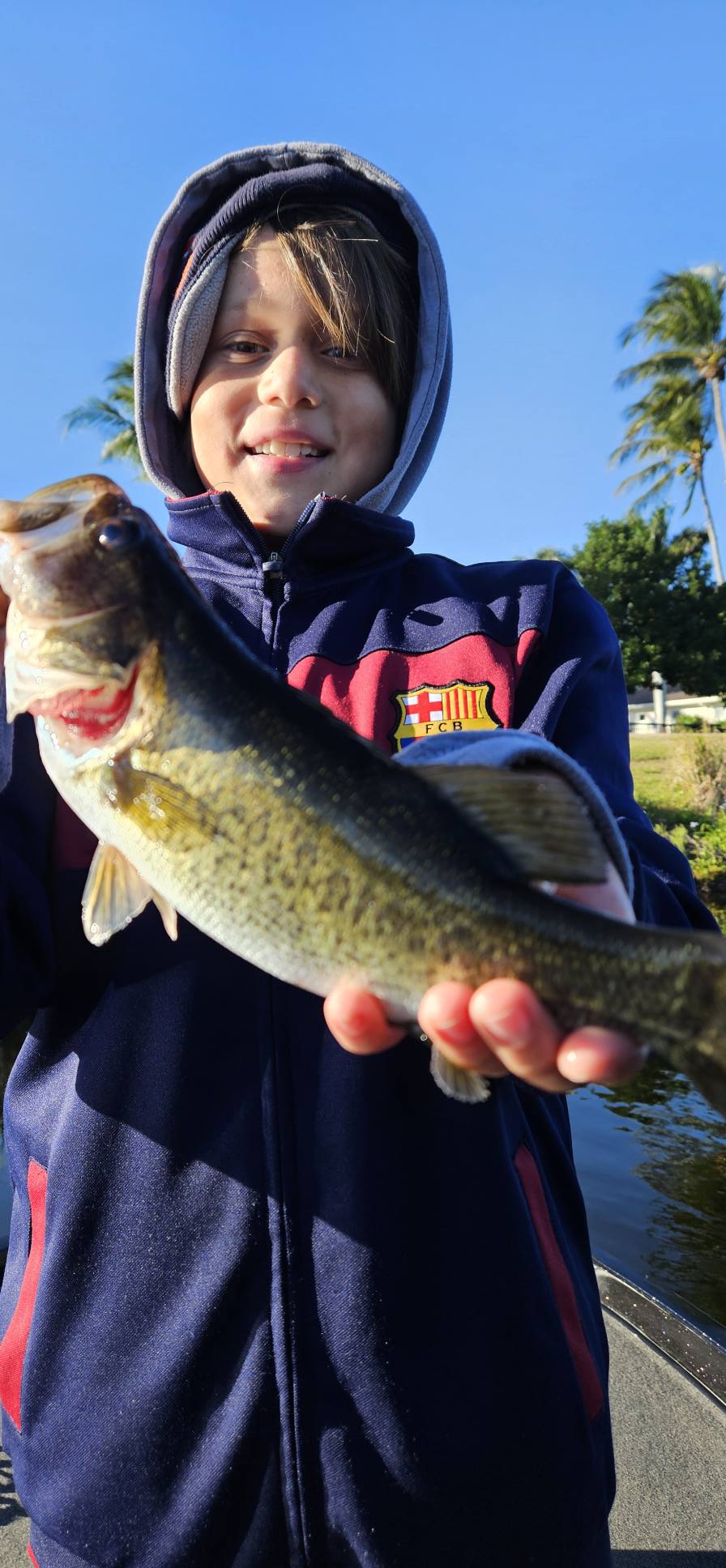 Young angler holding freshly caught bass while fishing in South Bay FL