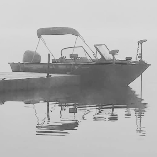 Fishing boat with canopy anchored on calm water with reflection visible