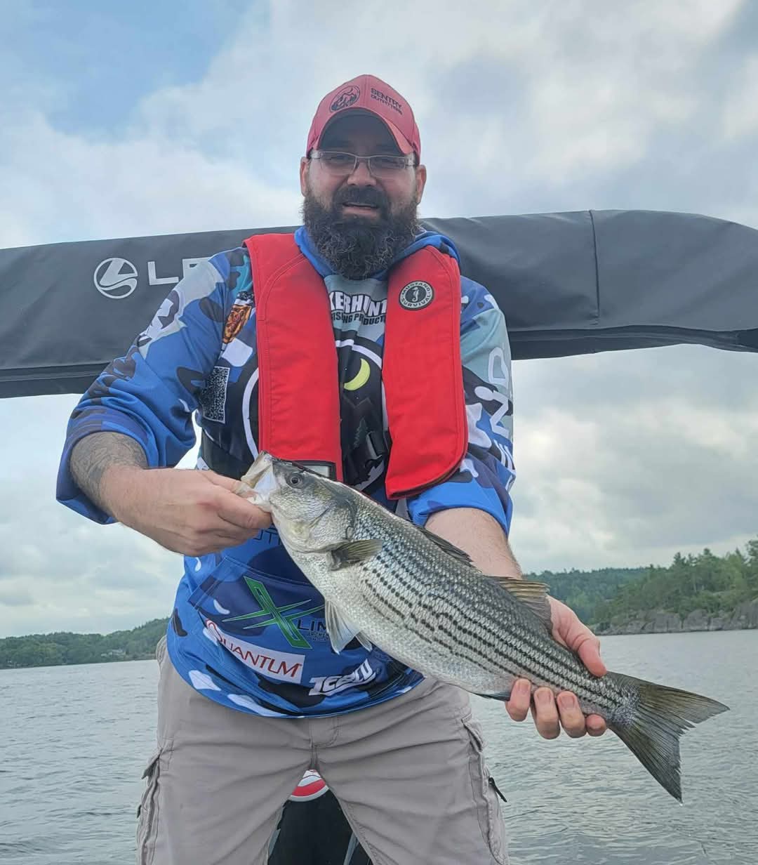 Angler holding freshly caught striped bass on fishing boat