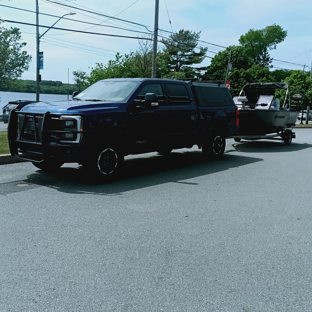 Black pickup truck towing boat on trailer in Lantz NS parking area