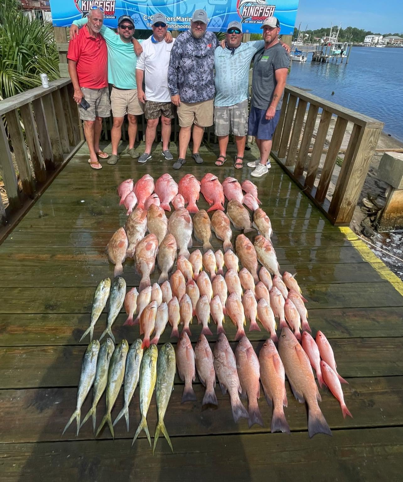 Large fishing catch display showing grey snapper and mahi mahi arranged on wooden dock in Carrabelle FL