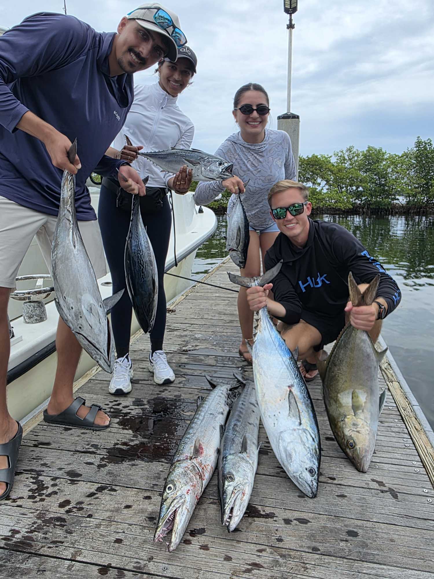 Successful fishing trip in Boynton Beach FL displaying caught longfin yellowtail, little tunny, and great barracuda on dock