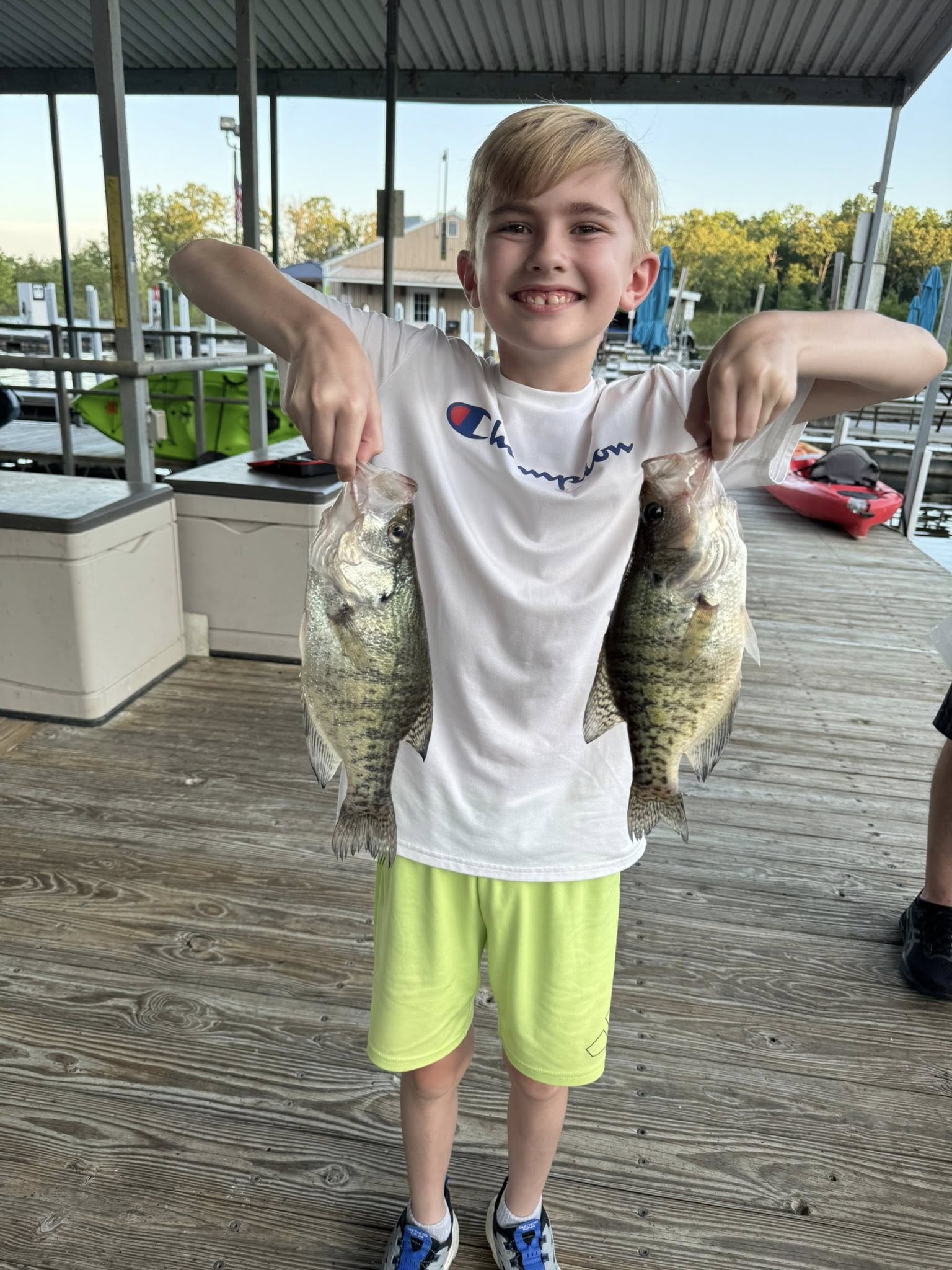 Two freshly caught bass displayed on wooden dock at Sand Springs OK marina