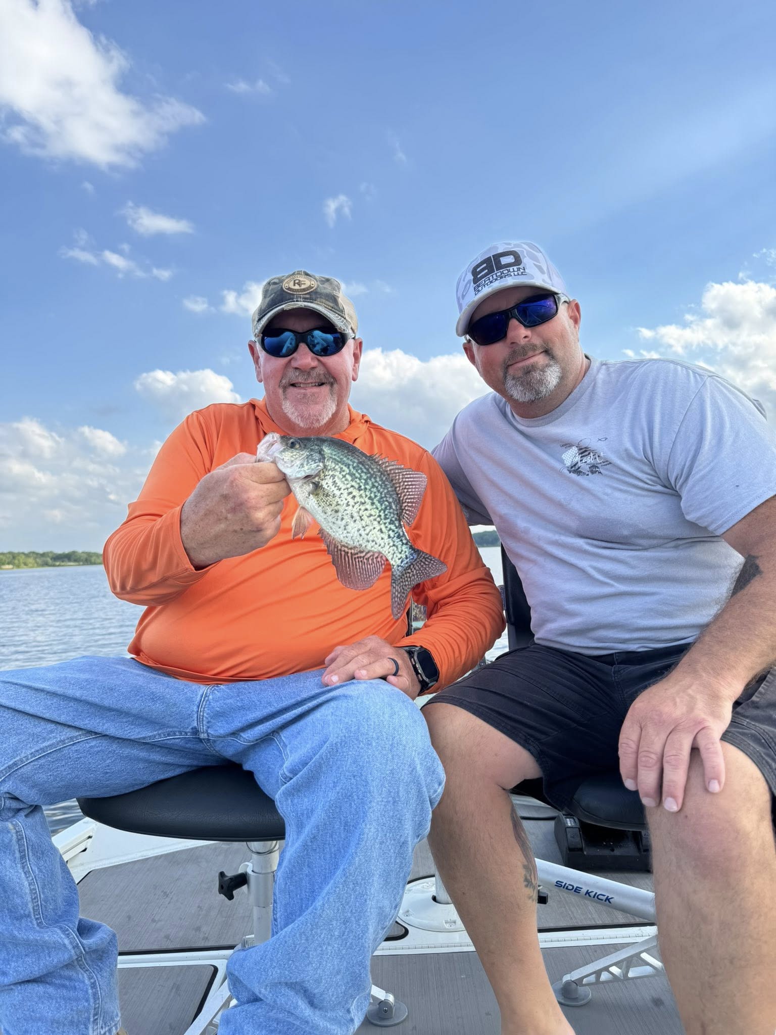 Two anglers holding a freshly caught crappie on a fishing boat in Sand Springs OK