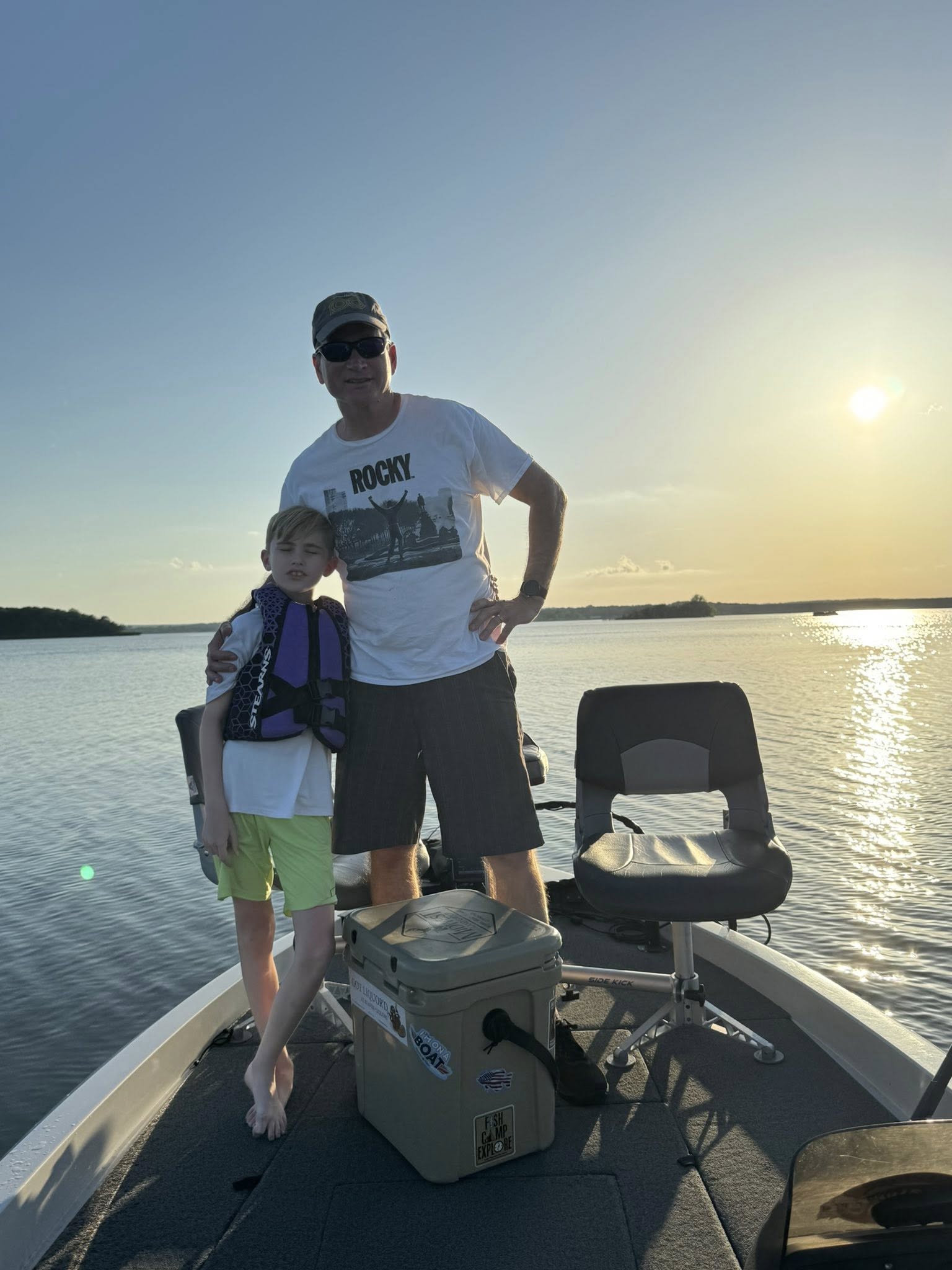Fishing boat on calm lake waters at sunset in Sand Springs OK with cooler and fishing chair