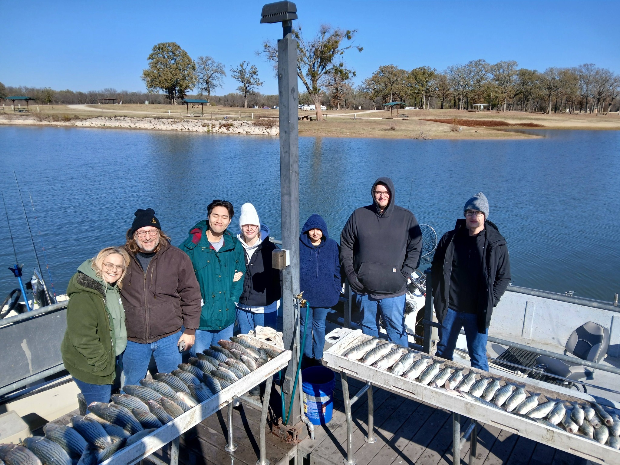 Fishing group displays large catch of striped fish on boat tables at Kingston OK lake