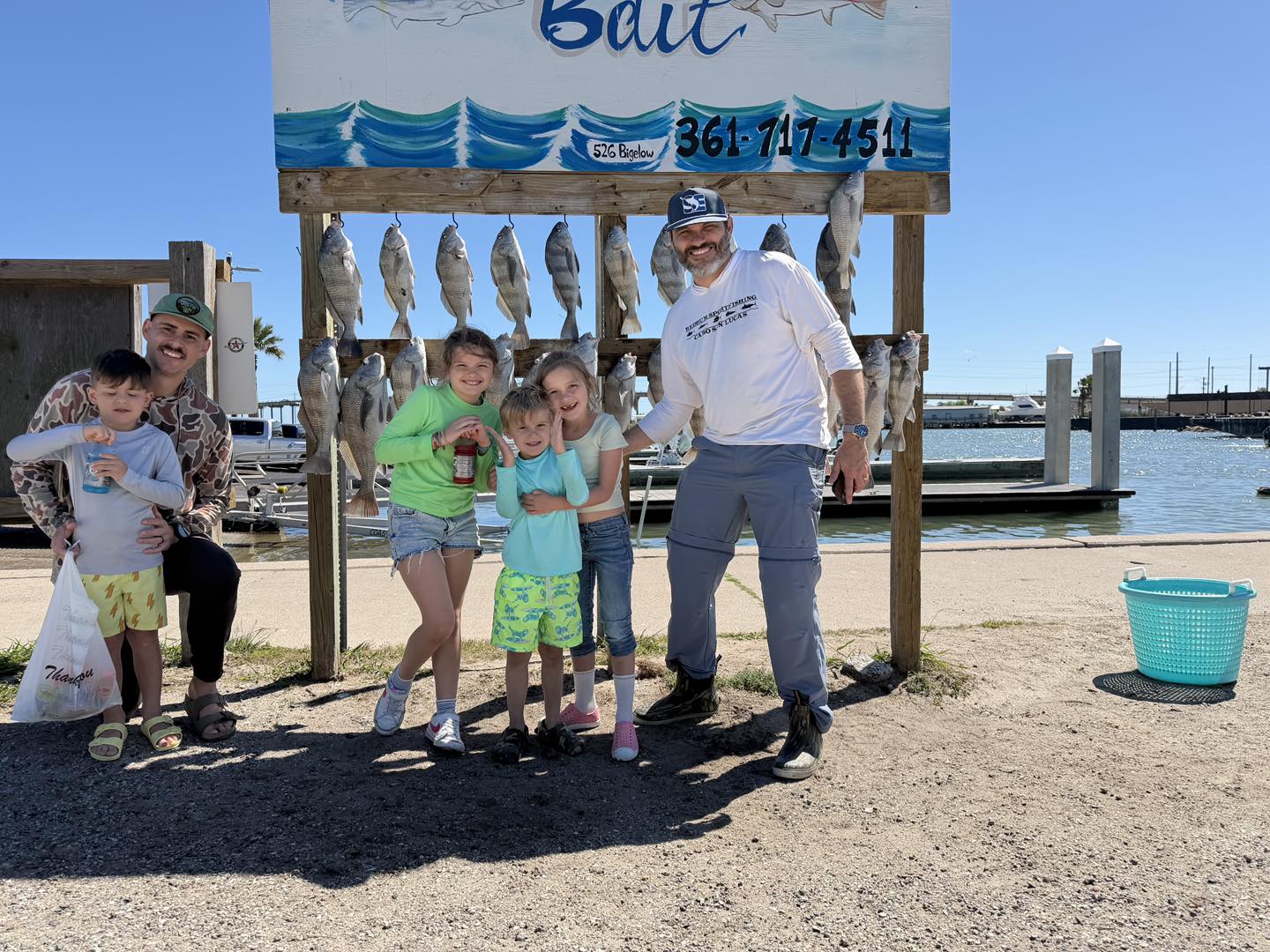 Family fishing trip displaying caught fish at cleaning station in Rockport TX marina