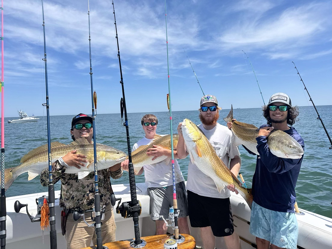 Four anglers display large redfish caught during fishing charter in Virginia Beach VA