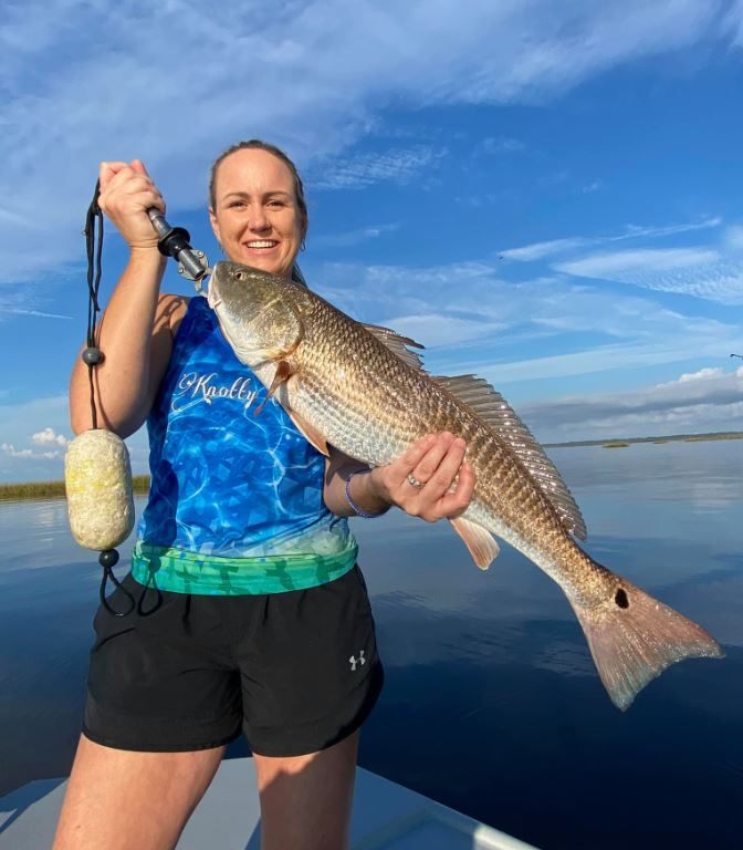 A fisherman holding a large redfish at Horseshoe Beach