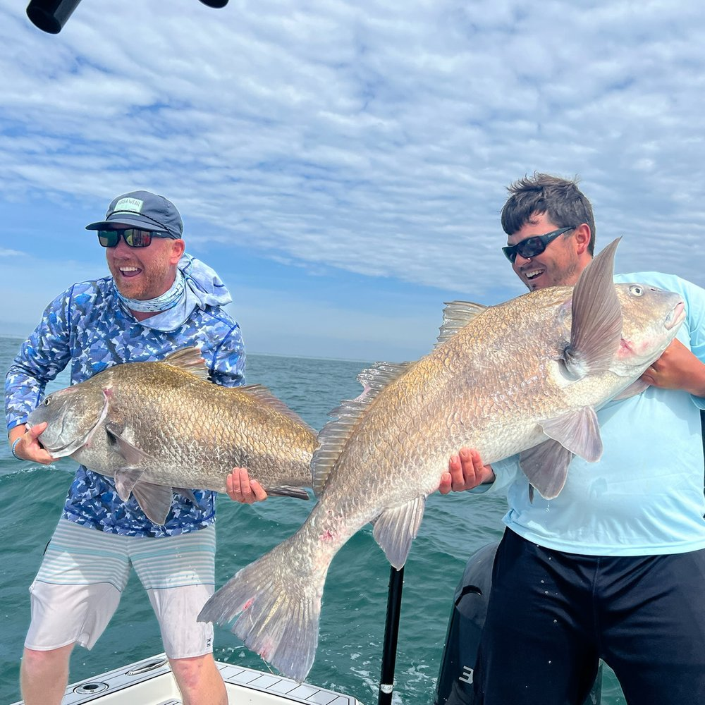 Two people fishing in Murrells Inlet, holding 30-inch fish