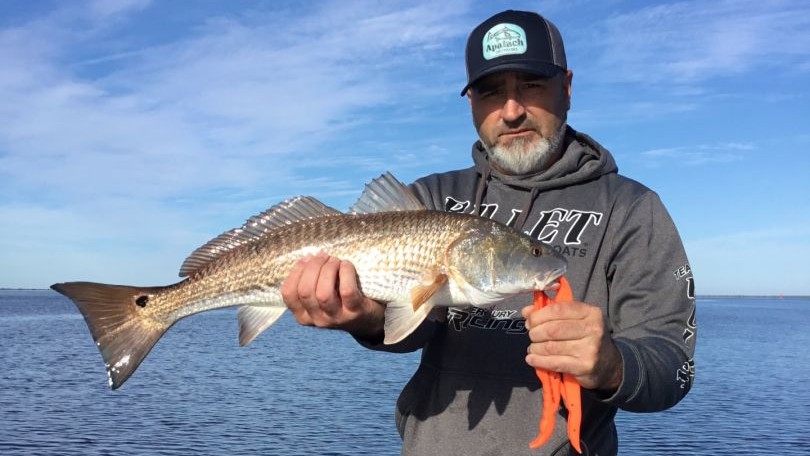 Angler holding caught redfish on boat in Florida waters