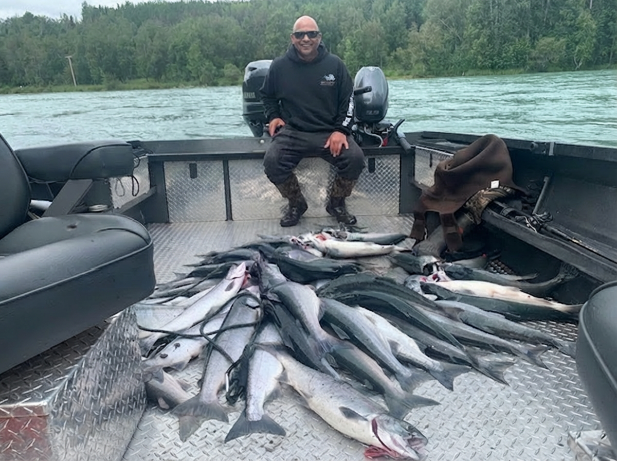 Successful fishing trip in Kenai Alaska showing large catch of salmon spread across boat deck