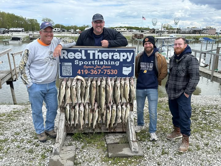 Successful fishing charter in Oregon OH displaying large catch of walleye on wooden rack at marina