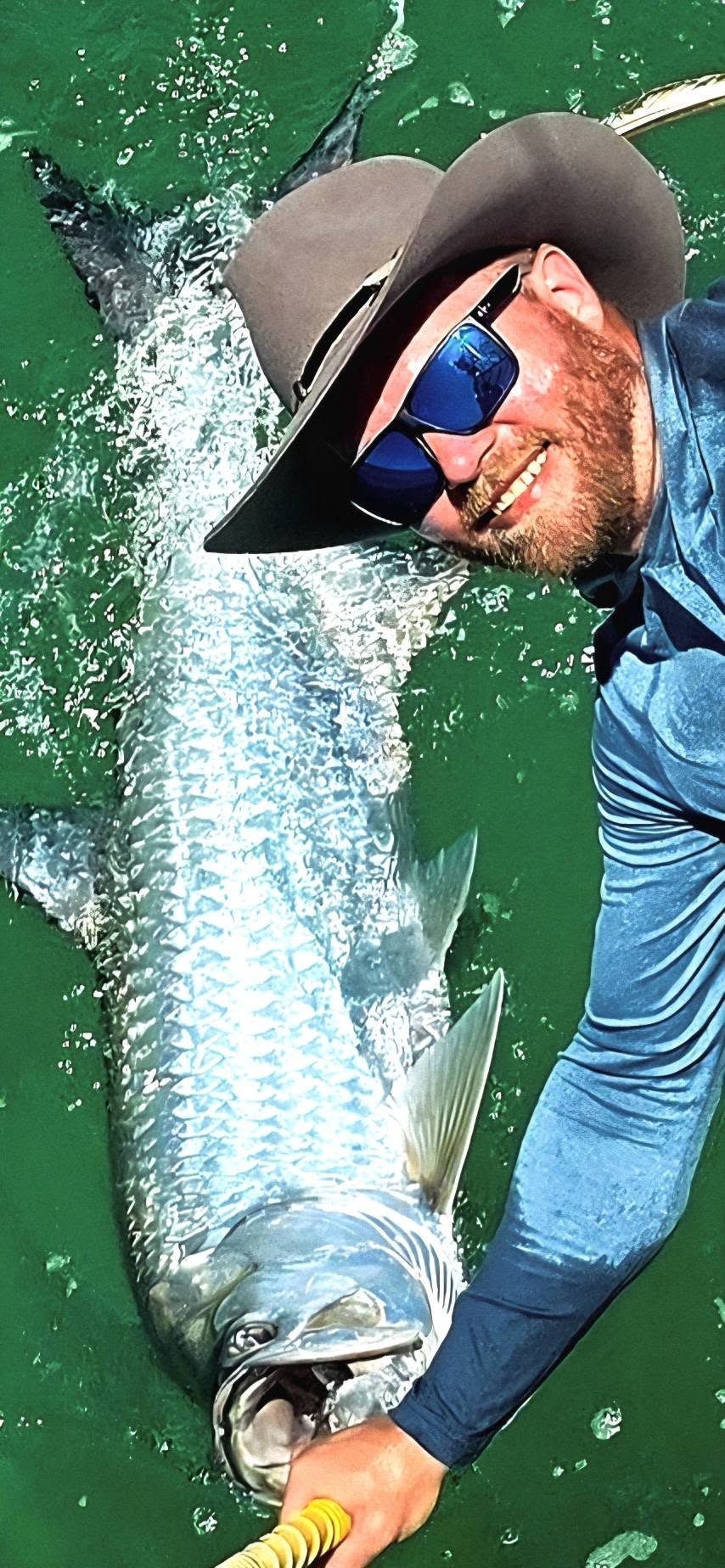 Large tarpon being held in green water after being caught while fishing in Destin FL