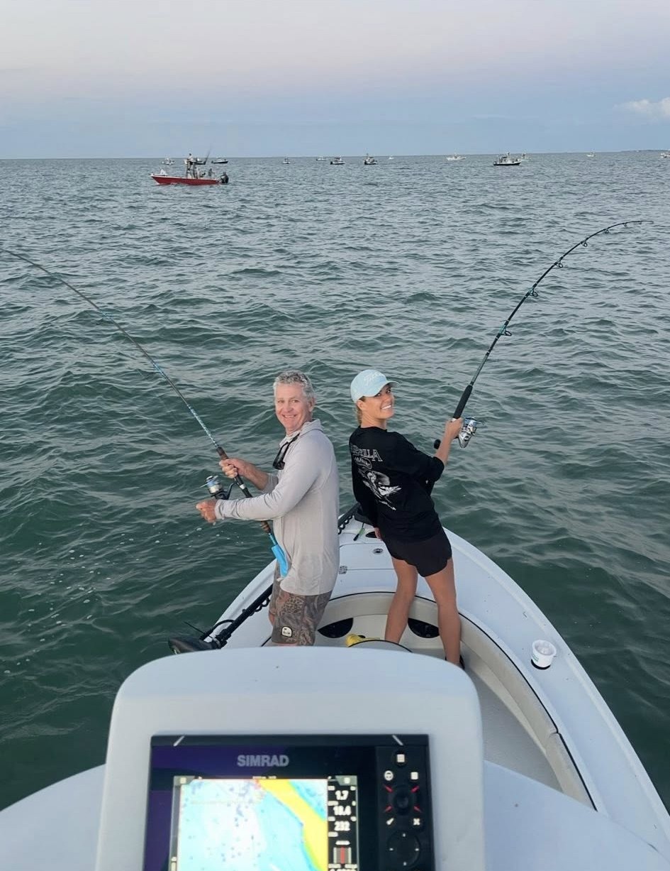 Two anglers fishing from boat with bent rods indicating fish on the line in Placida FL waters