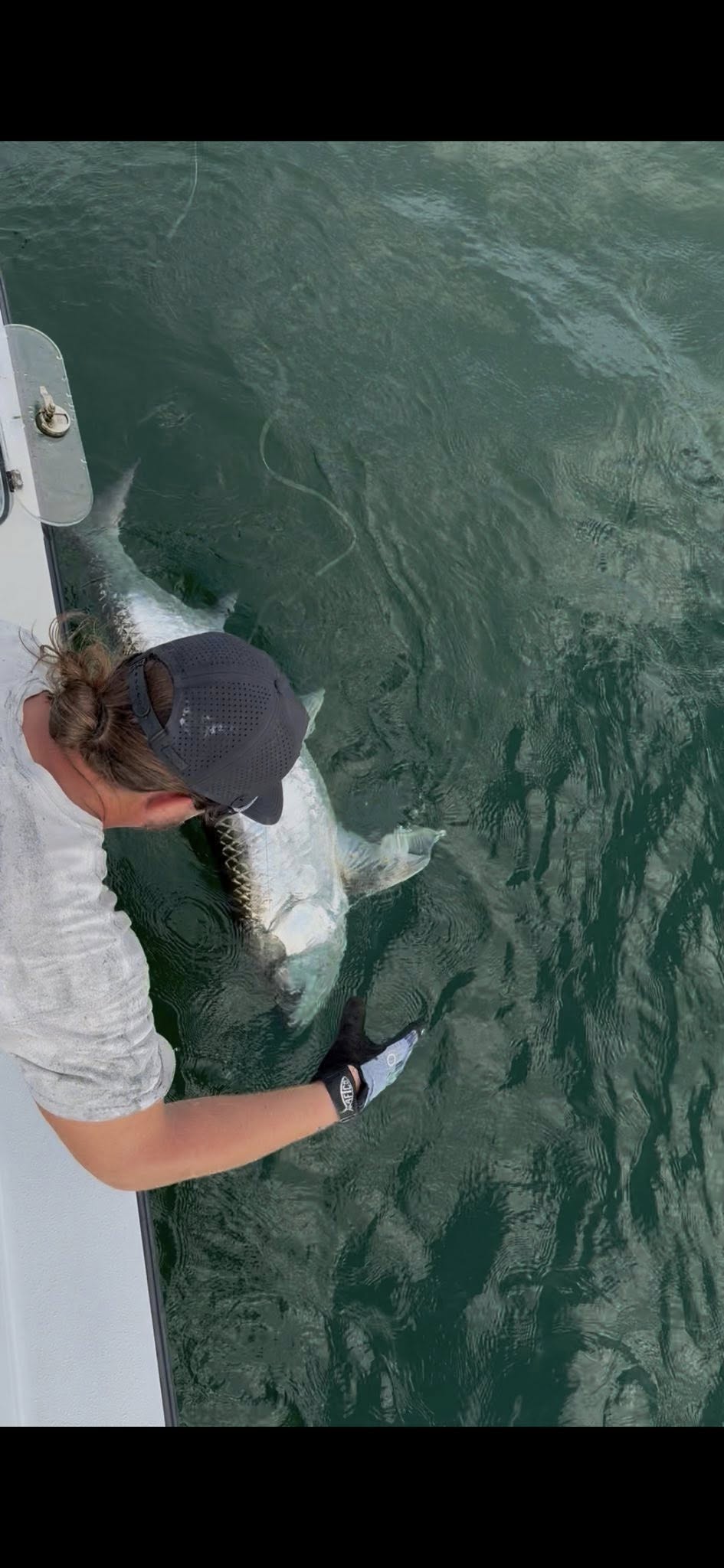 Angler releasing fish from boat in clear green water near Placida FL